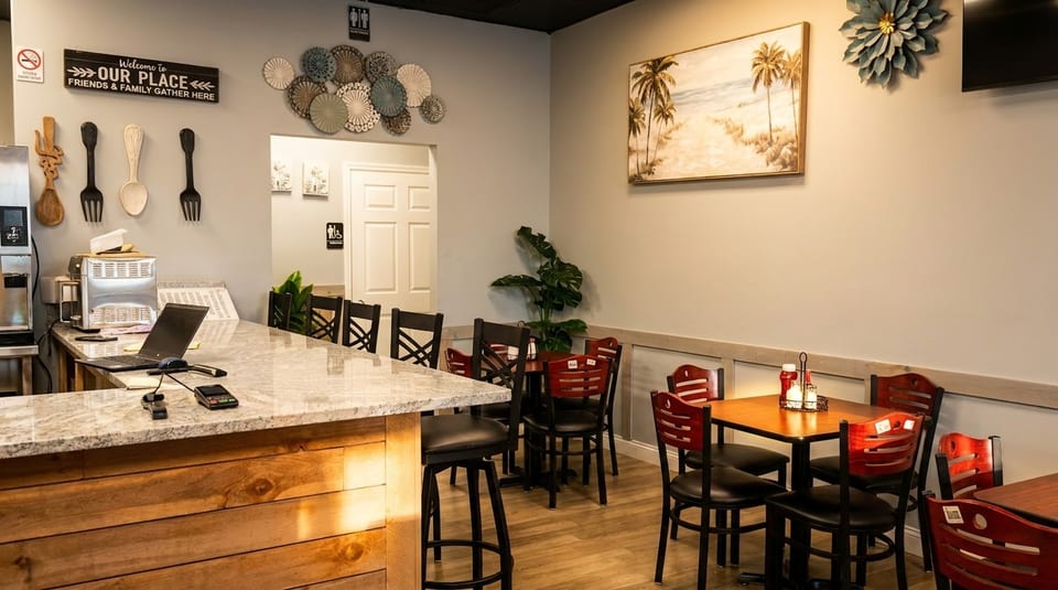 Restaurant interior with a counter, bar stools, dining tables, chairs, and wall decor.